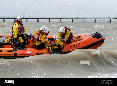 Rnli Crew Pulling A Fellow Crewman Aboard An Inshore Lifeboat From A