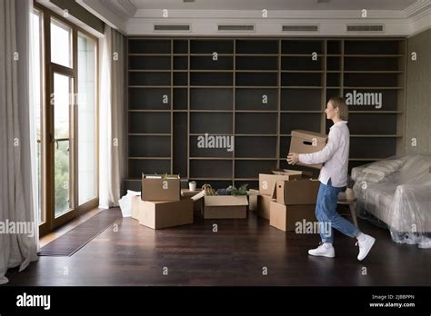 Woman Carrying Cardboard Boxes Into Living Room On Relocation Day Stock