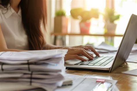 Female Professional Typing On Laptop Surrounded By Piles Of Tax