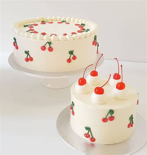 Two Cakes Decorated With Cherries And White Frosting