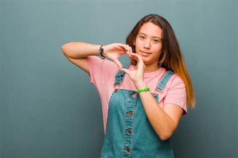 Joven mujer bonita latina sonriendo y sintiéndose feliz linda romántica y enamorada haciendo