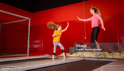 Happy Mother And Daughter Jumping On Trampoline In Fintess Center Stock