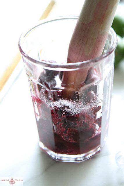 A Glass Filled With Ice And Liquid On Top Of A White Counter Next To A