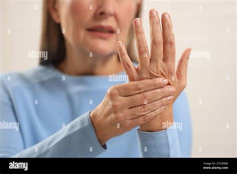 Mature Woman Suffering From Pain In Hand Against Light Grey Background