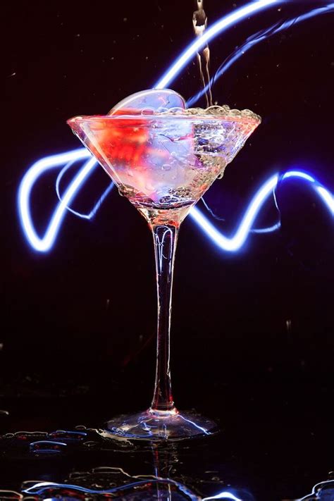 A Martini Glass Filled With Liquid On Top Of A Black Table Next To Blue