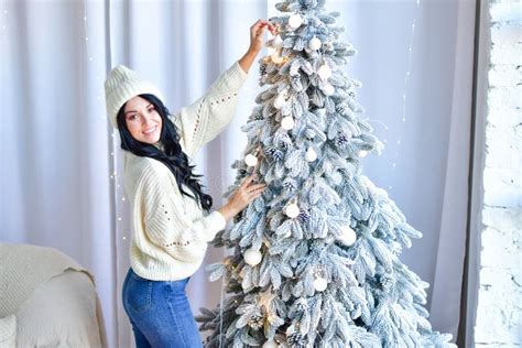 Brunette Girl In Sweater And Jeans In Front Of Her Christmas Tree Stock