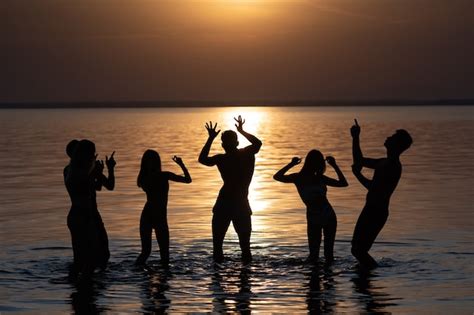 La Gente Bailando En La Fiesta Nocturna En La Playa Contra La Puesta De