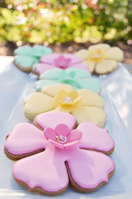 Decorated Cookies Are Lined Up On A White Tablecloth With Pink Blue