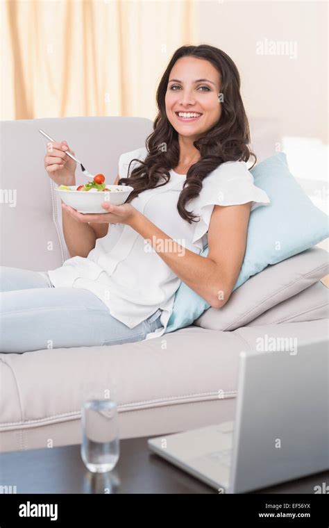 Pretty Brunette Eating Salad On Couch Stock Photo Alamy