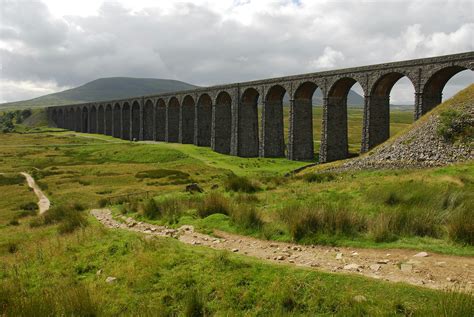 A train traveling over a bridge over a lush green field photo – Free