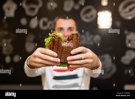 Closeup Funny Blurred Protrait Of Young Man Hold Bitten Sandwich By His