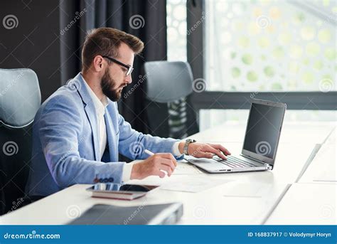 Successful Bearded Businessman In Glasses And In Blue Suit Works With