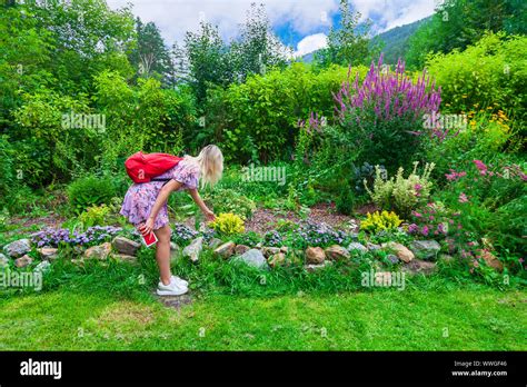 Une jeune fille blonde dans une robe rose avec un sac à dos rouge sur son dos et d un téléphone