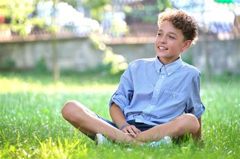 Menino criança feliz relaxando na grama verde no parque de verão