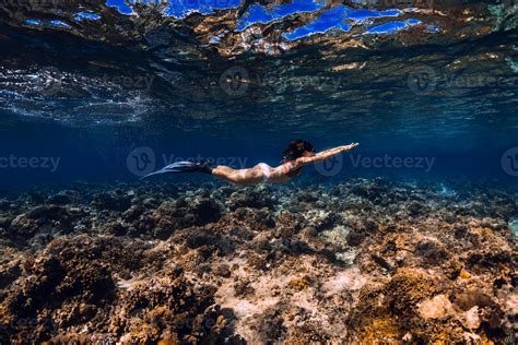 Woman Freediver With Fins Glides Over Coral Reef Underwater In Ocean