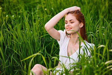 Cute Woman With Red Hair Sits In Tall Green Grass With Her Hand On Her Head Stock Image Image