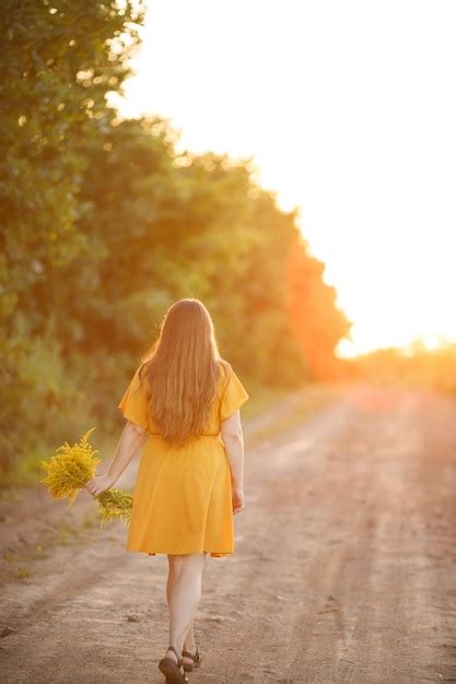 Premium Photo A Girl With Long Hair Walks In The Field With A Bouquet