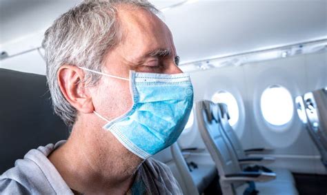 Middle Aged Man Wearing A Face Mask Sitting In An Empty Airplane Stock