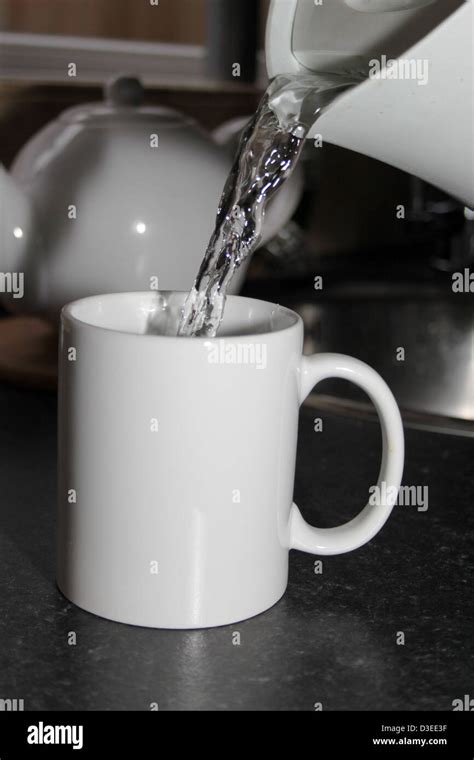 Boiling Water Being Poured From A Kettle Into A White Mug Stock Photo