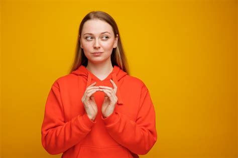 Tricky jeune femme blonde gardant les mains ensemble à côté Photo Gratuite