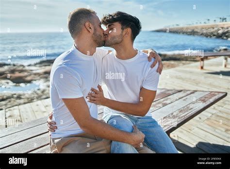 Un jeune couple gay s embrasse assis sur le banc à la promenade de la plage Photo Stock Alamy