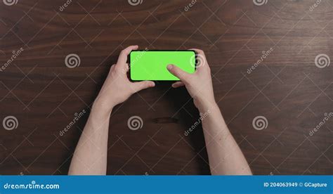 Top View Man Hand Use Smartphone With Green Screen Over Black Walnut