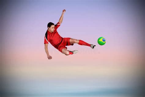 Composite Image Of Fit Football Player Jumping And Kicking Stock Photo