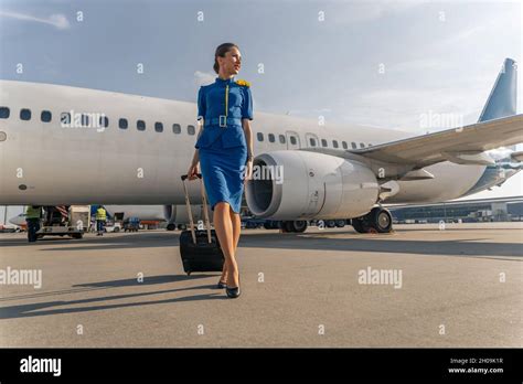 Female flight attendant walking with black suitcase Stock Photo - Alamy