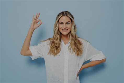 femme blonde détendue montrant un geste ok avec la main sur la hanche Photo de stock