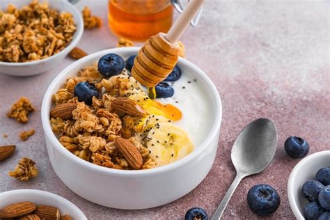 Premium Photo Pouring Honey Into The Bowl Of Greek Yogurt With