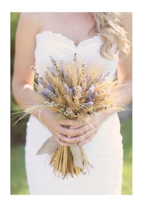 A Woman In A White Dress Holding A Bouquet Of Dried Wheat And Lavenders