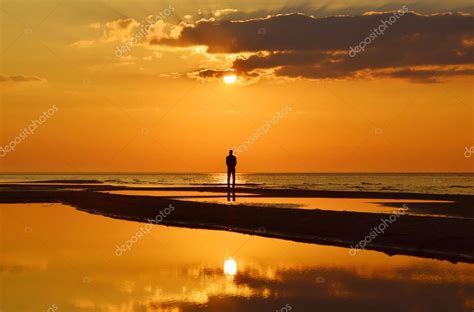 Silueta De Un Hombre Mirando La Puesta De Sol En Una Orilla Del Mar