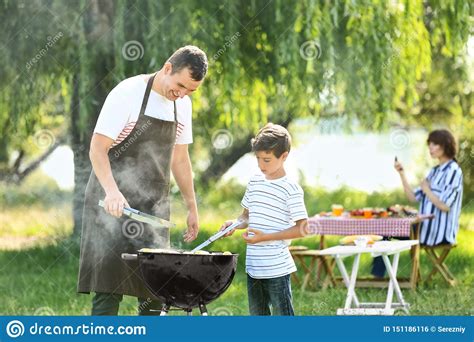 Little Boy With His Father Cooking Tasty Food On Barbecue Grill