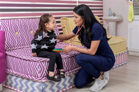 Pediatra latina revisa a una niña con su estetoscopio en su consultorio médico Foto Premium