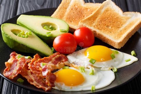 Hearty Breakfast Fried Eggs With Bacon Avocado Toast And Toma Stock