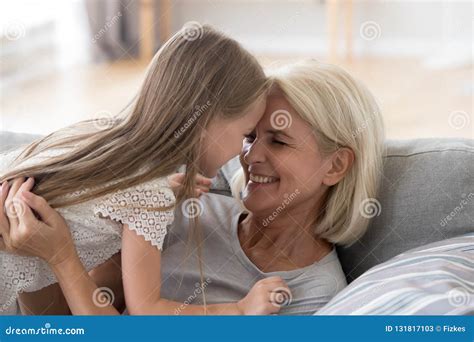 Cute Granddaughter Having Fun Playing With Grandmother Embracing Stock