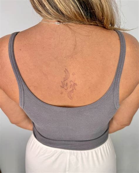 Two Opposite Fish Tattoo Located On The Upper Back