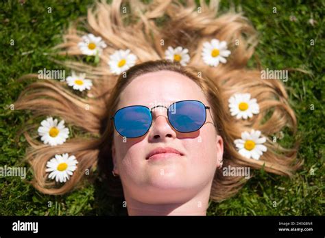 The Portrait Of Beautiful Woman In Sunglasses Lying In The Field With Chamomile Flowers In Hair