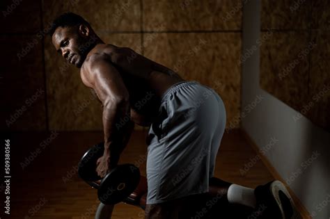 African American Man With Naked Torso Doing Triceps Row With Dumbbell