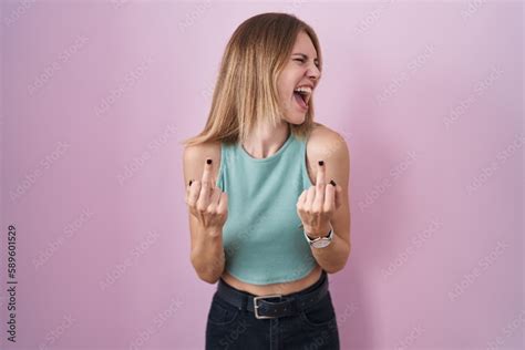 Blonde Caucasian Woman Standing Over Pink Background Showing Middle Finger Doing Fuck You Bad