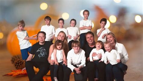 a group of children and adults posing for a family photo in front of pumpkins