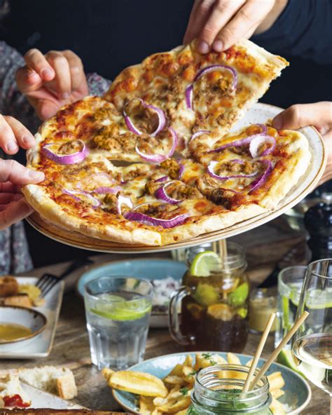 Mains Tendues Vers Des Parts De Pizza Avec Du Thon Sur Une Assiette