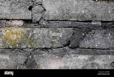 Vieux mur de briques gris en béton avec de la mousse qui pousse sur la