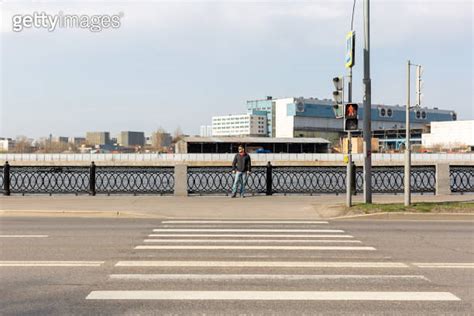 A man stands at a pedestrian crossing across the road 이미지 1313883434