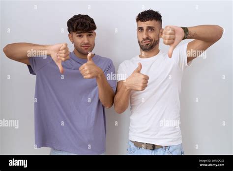 Homosexual gay couple standing over white background doing thumbs up ...