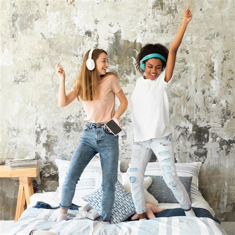 Free Photo Female Friends Dancing In Bed While Listening To Music On