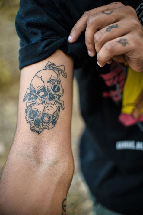 A Man With A Skull Tattoo On His Arm Holding Onto Another Person S Arm