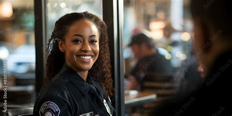 A Black female police officer chatting and smiling with colleagues ...