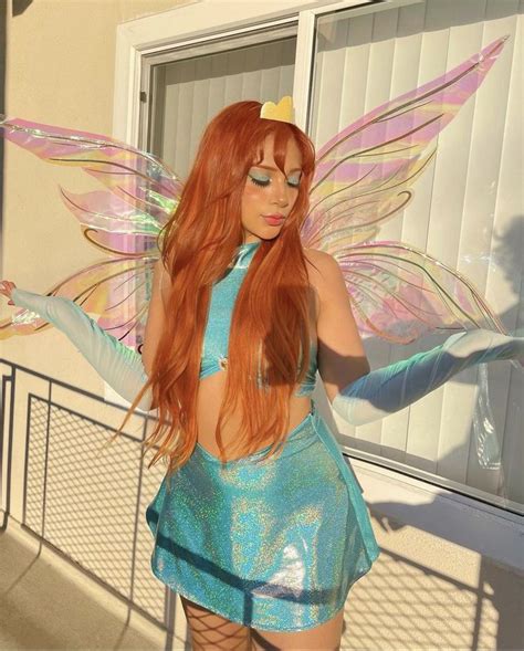 A Woman Dressed As A Fairy With Long Red Hair Wearing A Blue Dress And