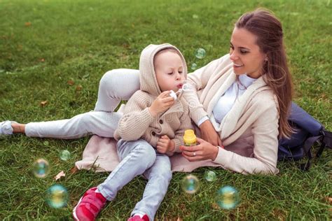 Mom Woman Plays With Child Little Boy Son Autumn On Street Blowing